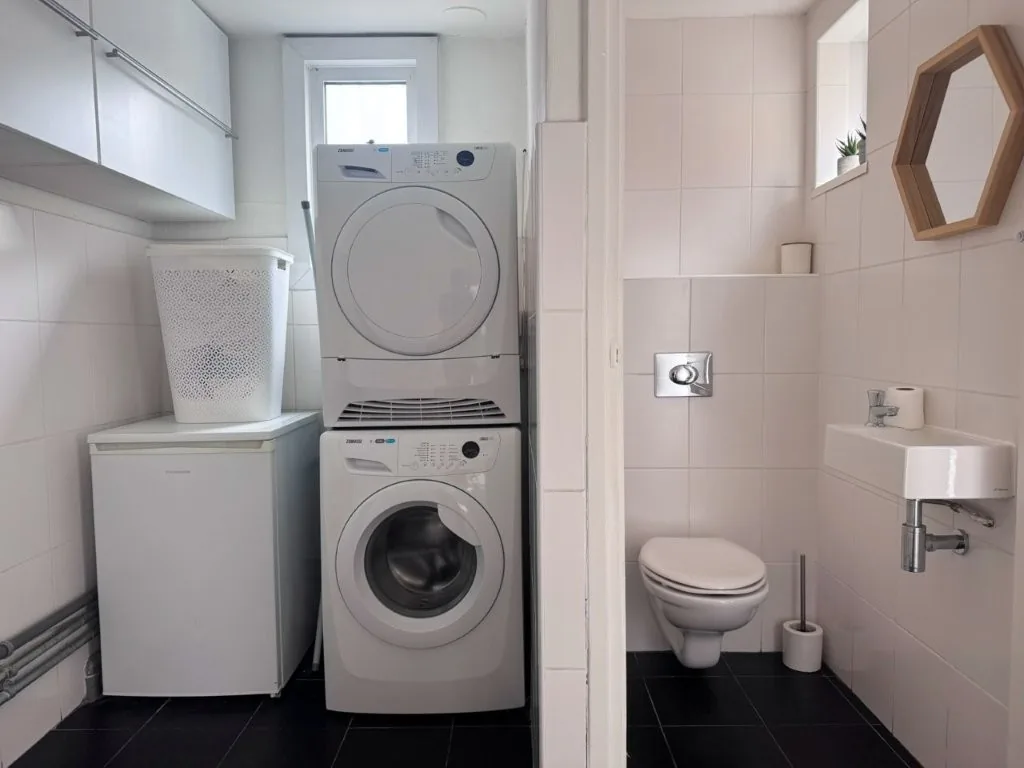 Bijkeuken met ruimte voor wasmachine en droger, en een toilet