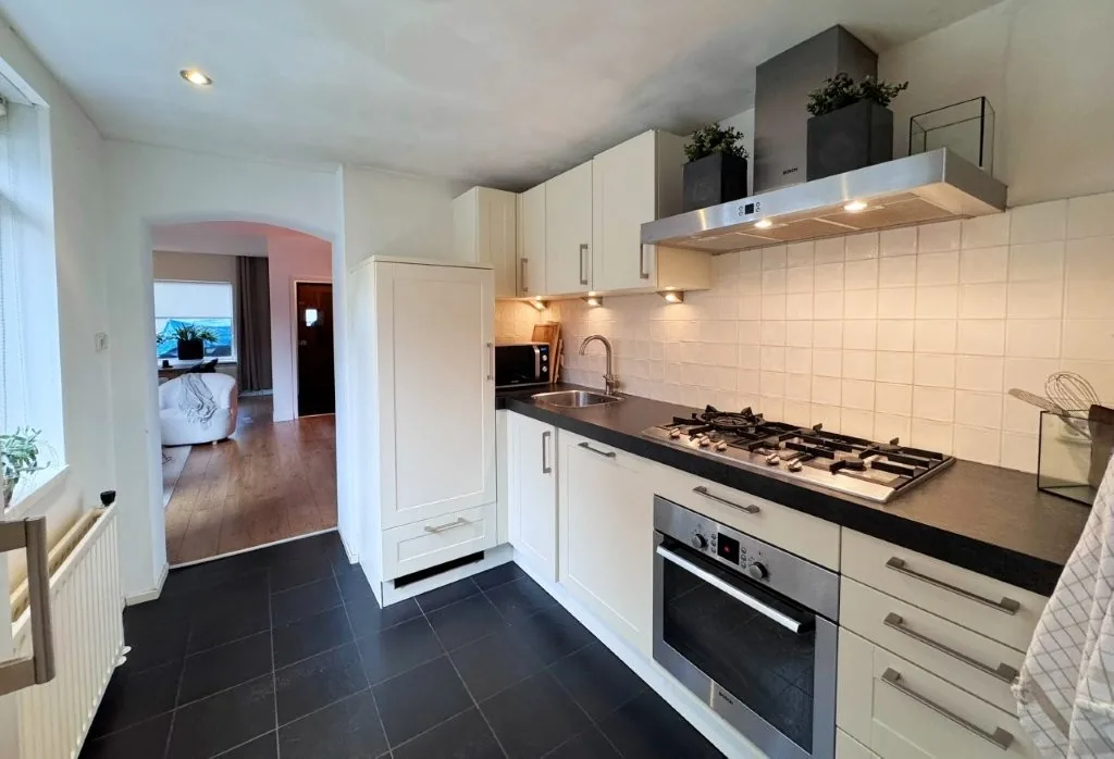 Witte keuken in de aanbouw met gaskookplaat, afzuigkap en inbouwoven