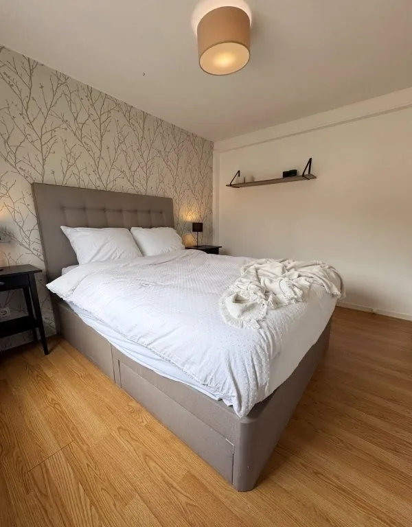 Slaapkamer met tweepersoonsbed en behang als accentwand